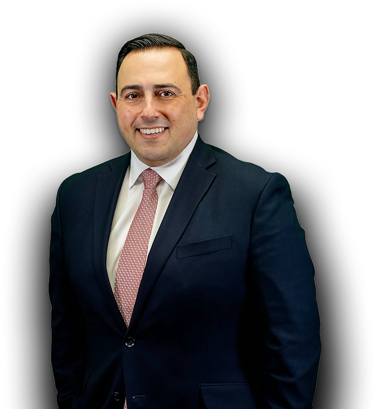 Antony Abboud smiles in a dark suit, white shirt, and patterned pink tie.