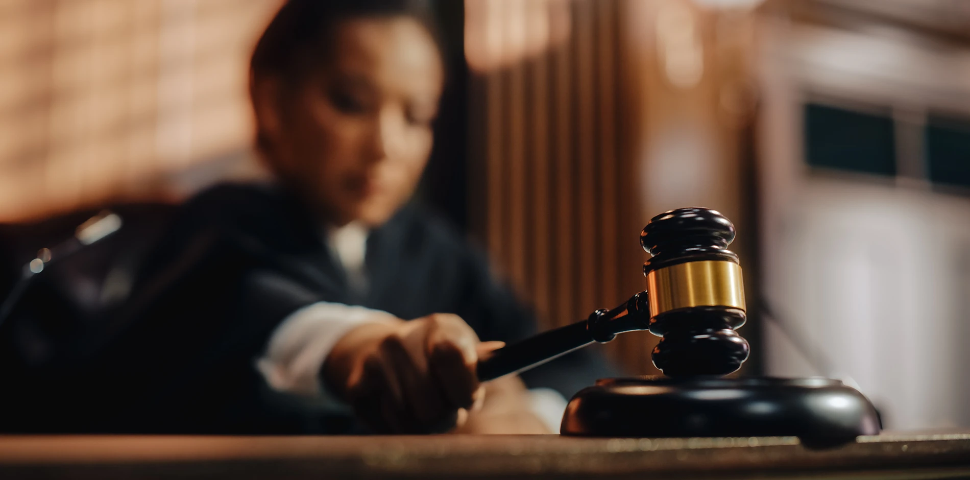 Fed's hand reaches for a wooden gavel on a desk, with Fed blurred in the background.