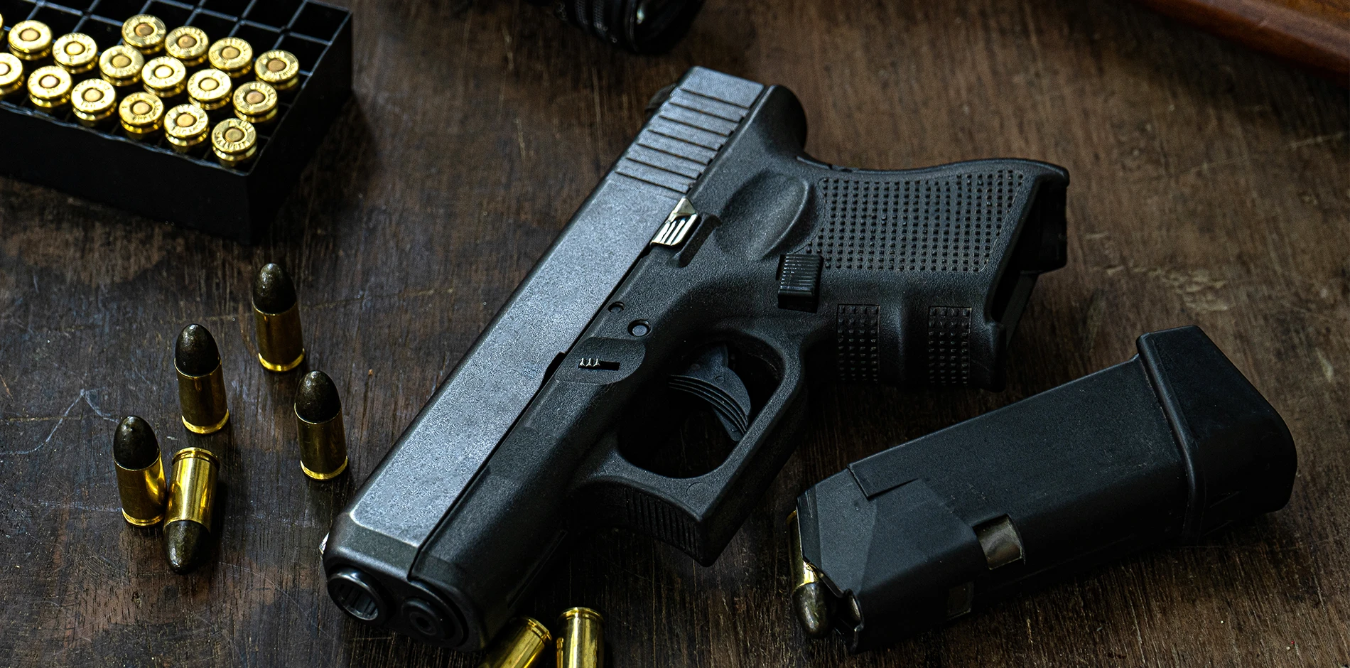 Weapons Desktop shows a black pistol with its magazine and various bullets on a rustic wooden table.